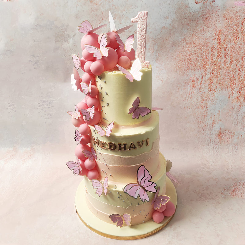 As your eyes dance upward this Butterfly Fault Line Cake, you'll be mesmerised by a cascade of pink spheres and shimmering silver pearls, guiding your gaze to the pinnacle of perfection. 