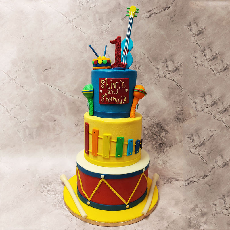 crowning this Drum cake for music lovers is an azure tier adorned with miniature confections: mics, tiny drums and a charming ukulele .