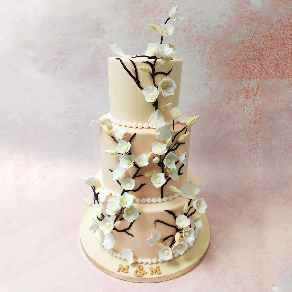 Each tier of this 3 Tier Pink Cake With White Flowers boasts a smooth light pink base, adorned with delicate edible white pearls encircling the bottom. 