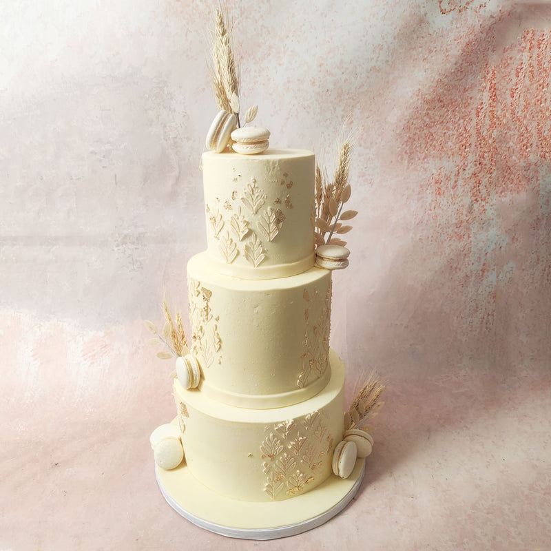 This 3 Tier White Cake is three tiers of pristine white, adorned with delicate buttercream leaves forming a subtle lace-like pattern that dances in the soft glow of romance. 