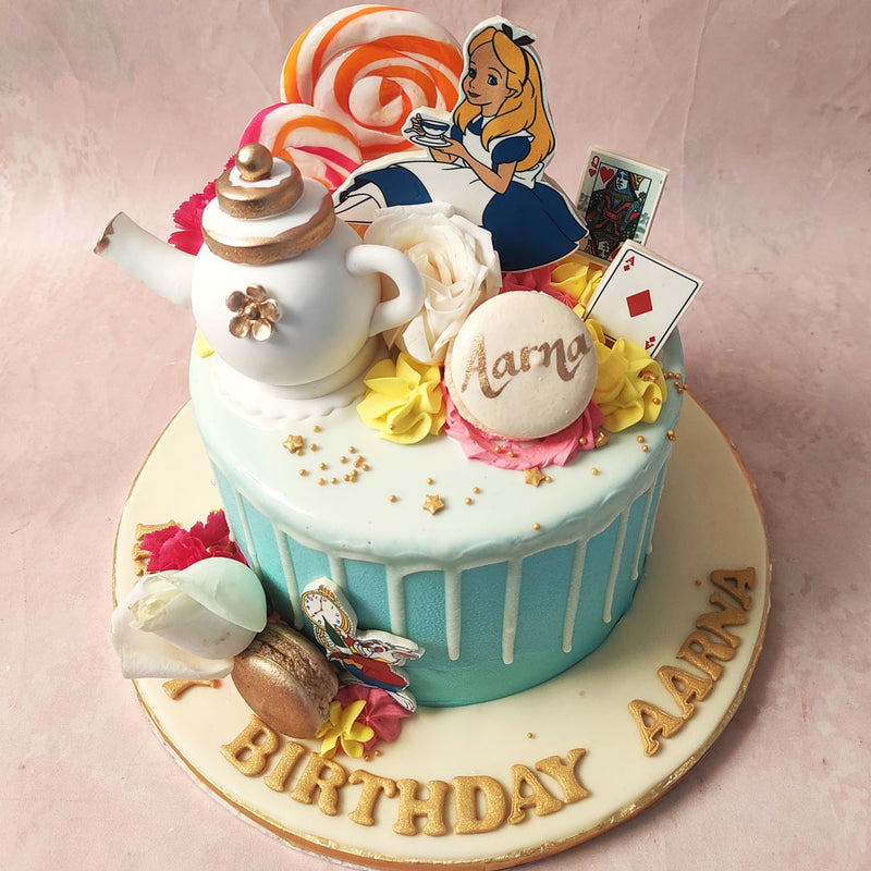 Next to her on top of this Rabbit Hole Cake, an edible teapot, the queen of hearts card, a white macaron and some spiral coloured lollipops. 