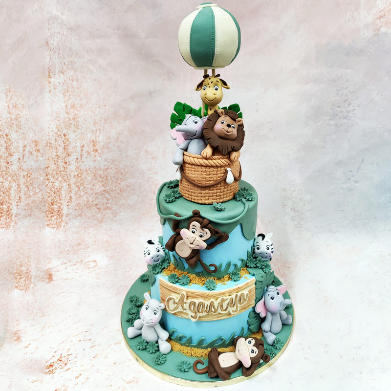 At the summit of this Animal Adventure Theme Cake, a charming mint-and-cream striped hot air balloon where charming jungle animals take flight. 