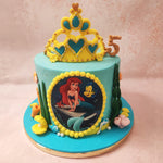 As you gaze further, your eyes will be drawn to the base of The Little Mermaid cake, where an array of aquatic treasures from the bottom of the ocean is delicately placed.  And finally, crowning this Disney theme cake is a yellow and blue tiara, reminiscent of Ariel’s iconic accessory.