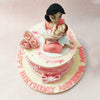 A figurine of a mother is seated on top of this baby shower cake, holding her little one in a pink blanket in her arms, adding to the beauty of the edible roses next to her. 