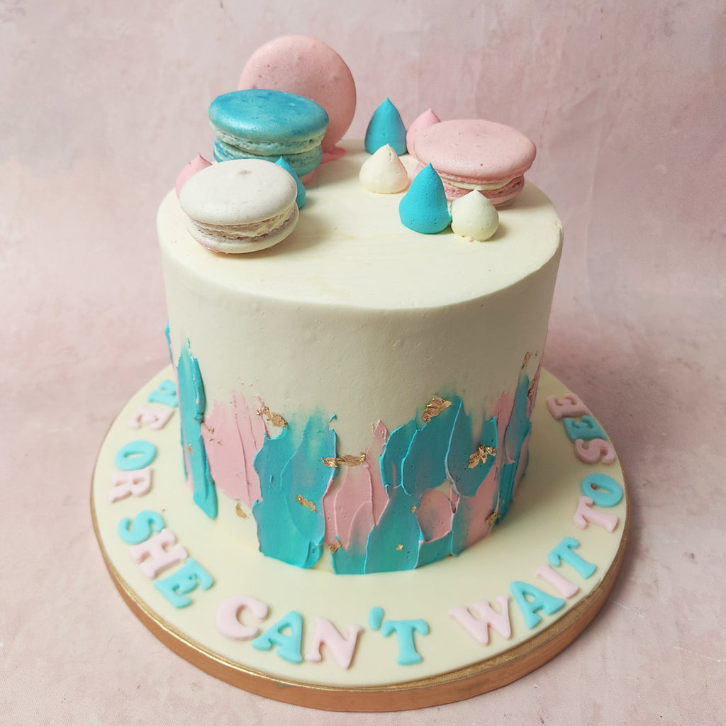 At the pinnacle of this Pink and Blue Buttercream Cake, white, blue, and pink macarons stand tall, each a symbol of the sweet moments awaiting the parents-to-be. 