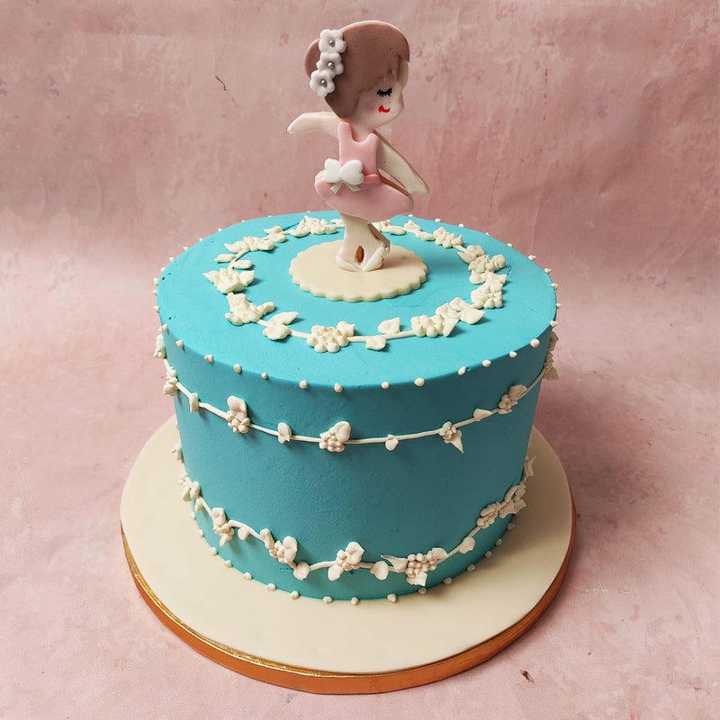 This Ballet Cake features a serene blue base adorned with a floral white wreath, gracefully encircling the circumference in lucious and velvety buttercream. 