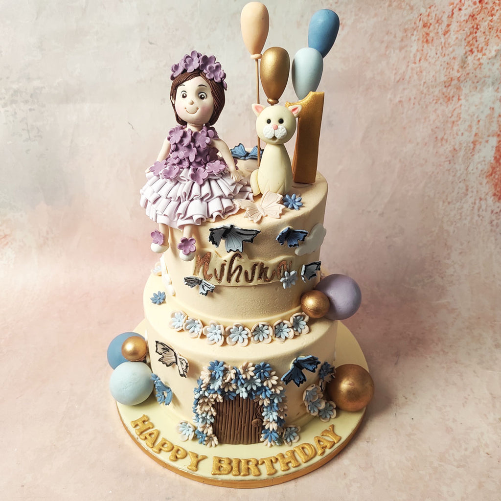The bottom tier features an edible figurine of a wooden door, enveloped in white and blue flowers, transforming the design of this Balloon Cake into a fairy's house. 