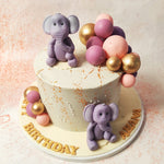 The pale, speckled base of this Elephant Theme Birthday Cake adds a touch of elegance, while the pink and gold balloon cluster adds a burst of colour and festivity.