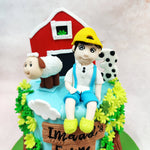 Sitting cheerfully at the top of this Barn Animals Cake is a boy in bright yellow boots, surrounded by a flock of friendly farm creatures and a bold red barn backdrop that pops with storybook charm.