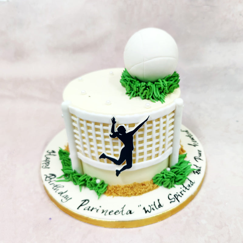 The focal point of this Volley Cake is a bold edible silhouette mid-jump—arms raised, ready for action—set against a 3D volleyball net that wraps around the front with clean, crisp tension. 