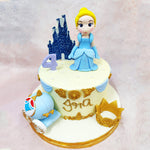 The handcrafted Cinderella figurine stands gracefully in the centre of this Birthday Cake For Girls, her powder-blue gown flowing with soft pleats that catch the light. Behind her, a sparkling midnight-blue castle silhouette sets the scene, adding depth and grandeur.