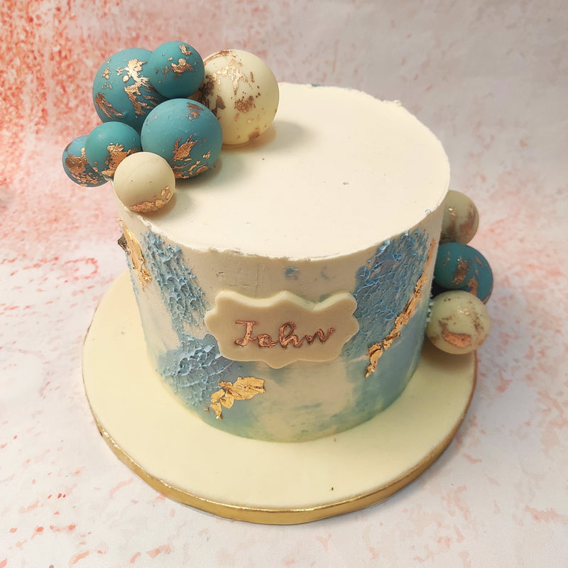 This Artsy Cake design, adorned with a medley of turquoise and white chocolate spheres, is an ode to refined artistry. 