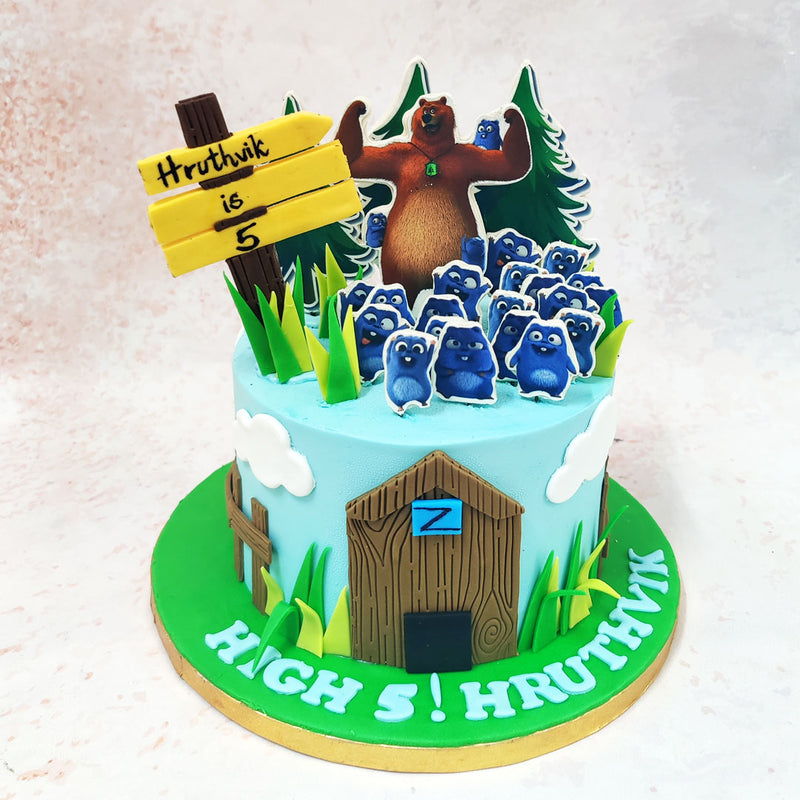 A rustic wooden cabin at the base of the Birthday Cake For Kids adds a charming touch, with its carefully detailed textures evoking the cosy hideaways of forest life.