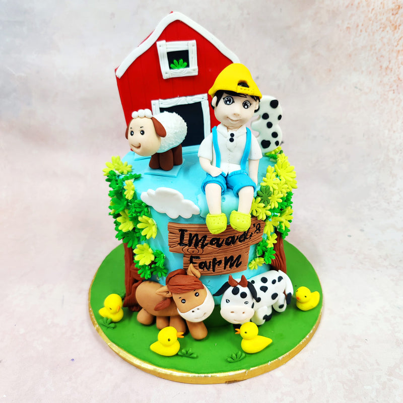 What grounds this entire Birthday Cake For Kids is the lush detail work—textured grass, puffy white clouds, sunflower-like foliage, and a wooden signboard marking the farm’s name. 