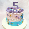 This two-tiered Birthday Cake For Kids harmoniously blends soft pastel hues, with a dreamy pink base adorned with expertly piped lavender rosettes crowning the top tier. 