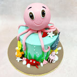 The soft, pastel aqua blue of this Sea Creatures Cake base dons a host of delightful sea friends, including a cheerful red crab, a tiny orange fish, and a cute squid, each intricately crafted to bring the marine world to life.