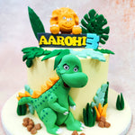 The adorable green dinosaur front and centre on this Birthday Cake For Kids—with its goofy grin, expressive eyes, and playful stance—bears more than a passing resemblance to Littlefoot’s cheerful companions from The Land Before Time, stirring up fond memories for parents and sparking curiosity in kids.