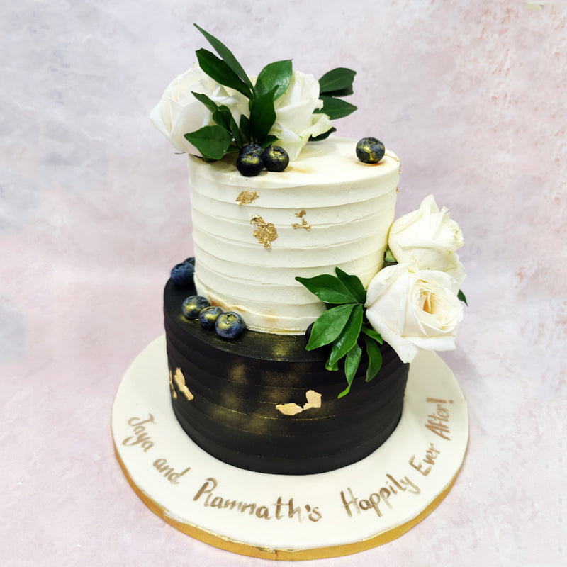 This elegant two-tiered Black and White Floral Cake showcases a sophisticated contrast of cream and black, perfect for a wedding celebration with modern flair. 
