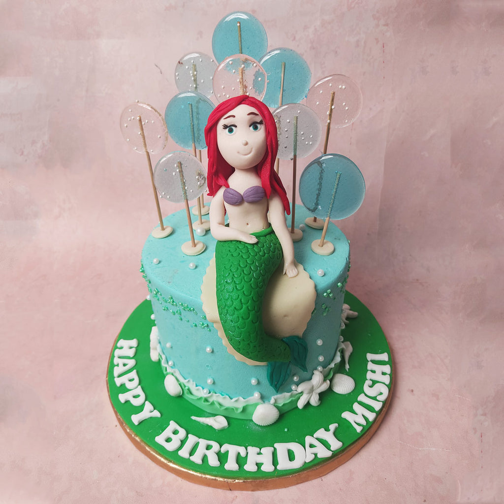 The light blue sea serves as the canvas of this Blue Mermaid Cake, adorned with enchanting translucent lollipops, creating ripples of magic in every glance. 
