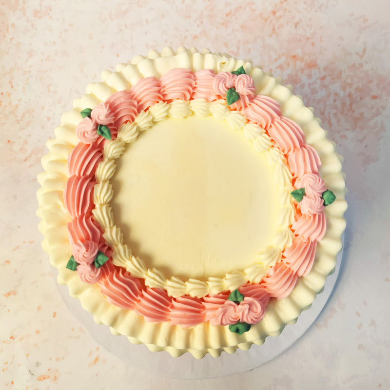 The fondant drapes, adorned with charming pink swags and tiny rosebuds, add a touch of sophistication to this Buttercream Frill Cake symbolising grace and beauty. 