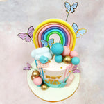  Perched atop this Butterfly Boy or Girl Cake is a miniature rainbow crafted in pastel hues—yellow, peach, pink, blue, and mint—representing the promise and hope that accompanies new beginnings.