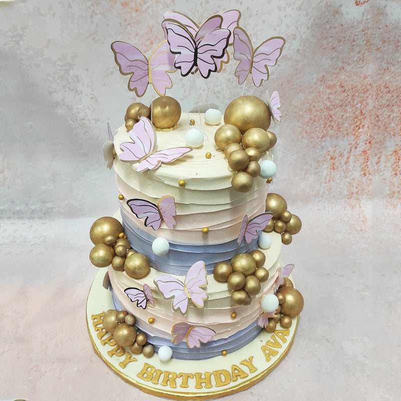 Gold baubles are scattered across this  pastel butterfly cake like stars across the evening sky, 