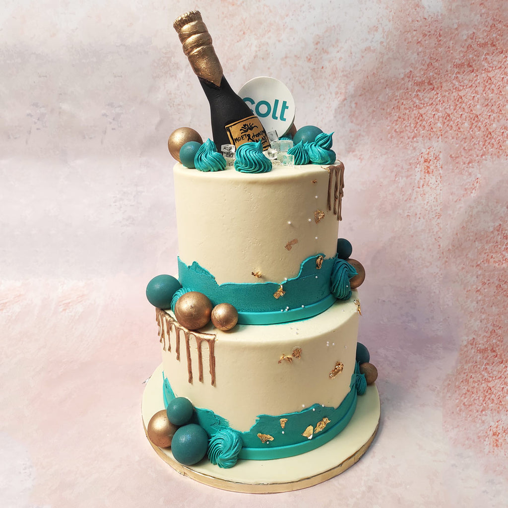 This exquisite Celebration Cake design boasts two tiers of creamy elegance, adorned at the bottom with an abstract blue border resembling a fault line, adding a touch of drama to its opulent design. 