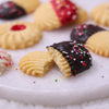 Christmas butter cookie broken in half, showing the rich, crumbly texture and dark chocolate dip with colorful festive sprinkles.