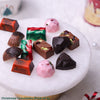 Assorted Christmas chocolates on a white plate with decorative elements.