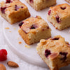 Assorted Christmas Raspberry Almond Financier squares topped with slivered almonds and fresh raspberries.