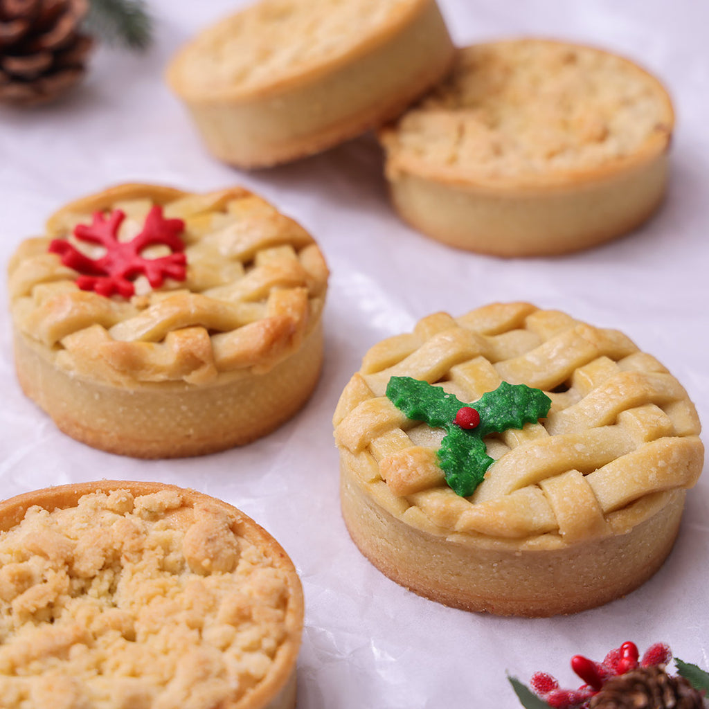 Assorted Christmas Pies with lattice and crumb tops, with holly and reindeer decor