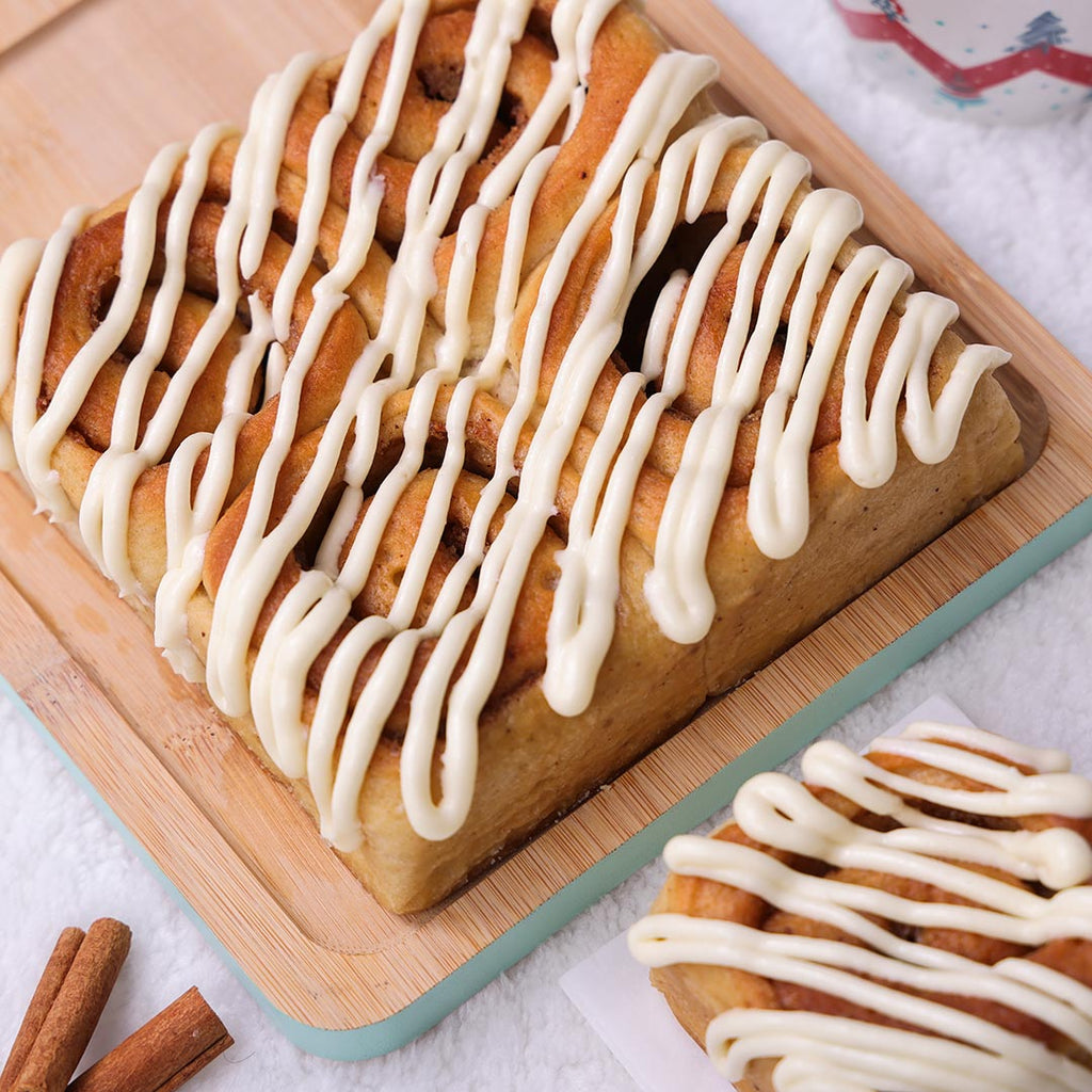 Freshly baked platter of Cinnamon Rolls covered in thick cream cheese icing, perfect for a cozy Christmas breakfast.