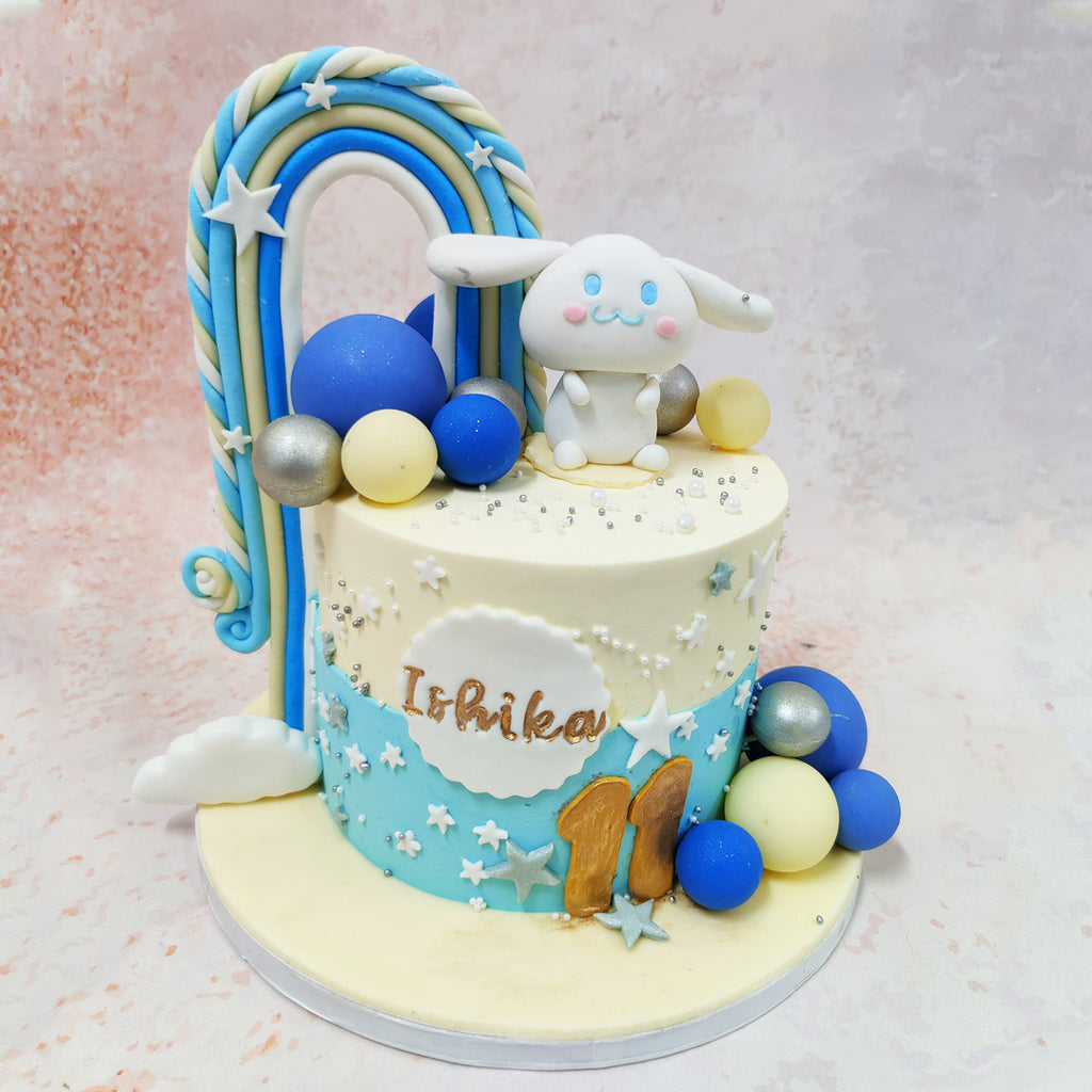 The towering pastel rainbow, with its intricate swirls of blue, white, and gold, forms an enchanting arch over this Cinnamoroll Cake, evoking the beauty of sunny skies after the rain. 