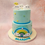This two tier rainbow theme cake is frosted in baby blue with a dark blue ribbon running around the centre. 