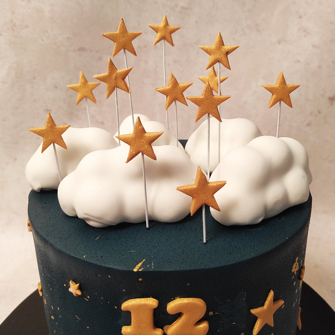 Blue birthday cake with meringue clouds, fondant crown and chocolate clouds,  poured with melted white chocolate Stock Photo - Alamy