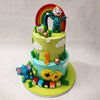 This two tier Cocomelon birthday cake for kids is set in the great outdoors, with a sky-blue bottom tier and grassy green top tier, both embellished with clouds passing through and around the circumference. 