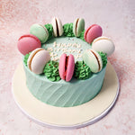 The smooth, pastel green icing sets the tone of this Macaron Birthday Cake For Husband, beautifully complemented by an array of colourful macarons carefully placed around the top. 