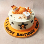 Garfield, the beloved orange tabby of this comic theme cake, grinning with that signature flair, lounges on his side. 