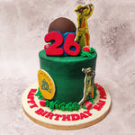 The design of this Dhoni cricket cake features two figurines of Dhoni, one at the top and another at the bottom, both donned in matching yellow attire. 
