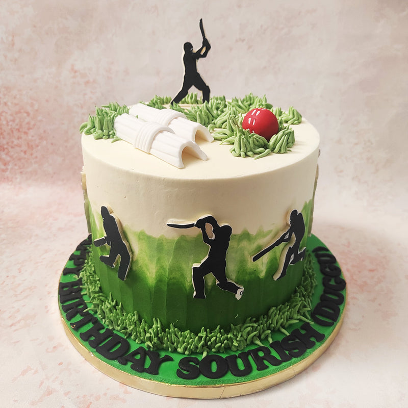 Atop this Cricket Field Cake, a striking scene awaits: a cricketer poised to make a winning shot, with the classic red cricket ball and wicket bails adding a touch of realism and nostalgia. 