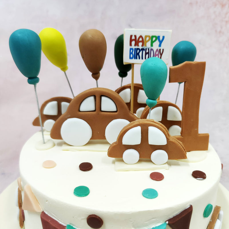 Topping this Cute Car Cake With Balloons is a parade of fondant cars in soft, earthy tones—complete with oversized white wheels, rounded edges, and a whimsical crew of balloons bobbing behind them. 
