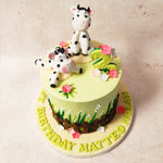 Picture a lush green base adorned with brown fences and delicate white flowers, as if the meadow itself had been captured in cute cow cake form. 