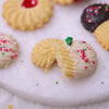 Close-up of a Danish-Style Butter Cookie broken in half, showing the crumbly texture and white chocolate icing dip with festive sprinkles.