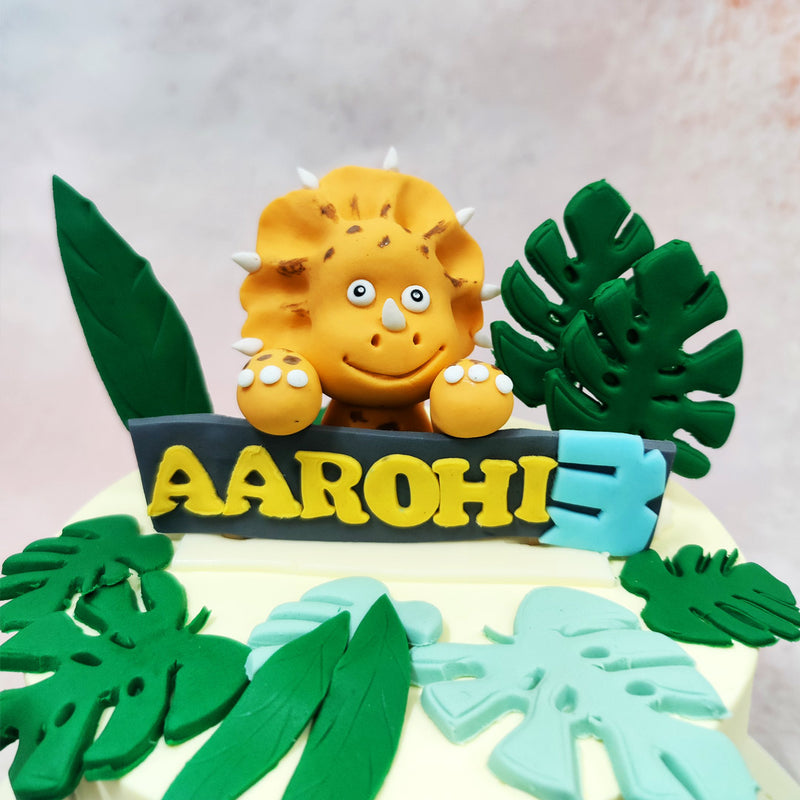 Towering jungle leaves in lush shades of emerald and mint wrap around the top and sides of this Dino Theme Cake, setting the scene for an adventure that feels straight out of a beloved dino tale. 