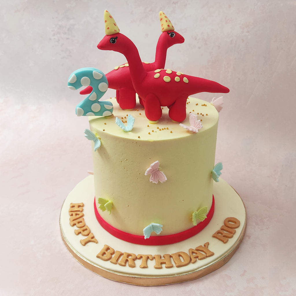 Featuring a white base with two cartoon-like dinosaurs on top, this red dinosaur birthday cake for kids creates the look and feel of a nursery with the dinos resembling stuffed toys one might find in their little ones crib.