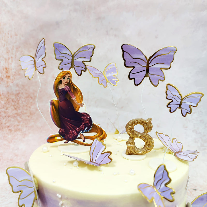 Adorning the top of this Disney Princess Cake is a charming figure of the spirited princess herself, her iconic golden locks flowing gracefully, dressed in her signature purple gown that captures her royal essence. 