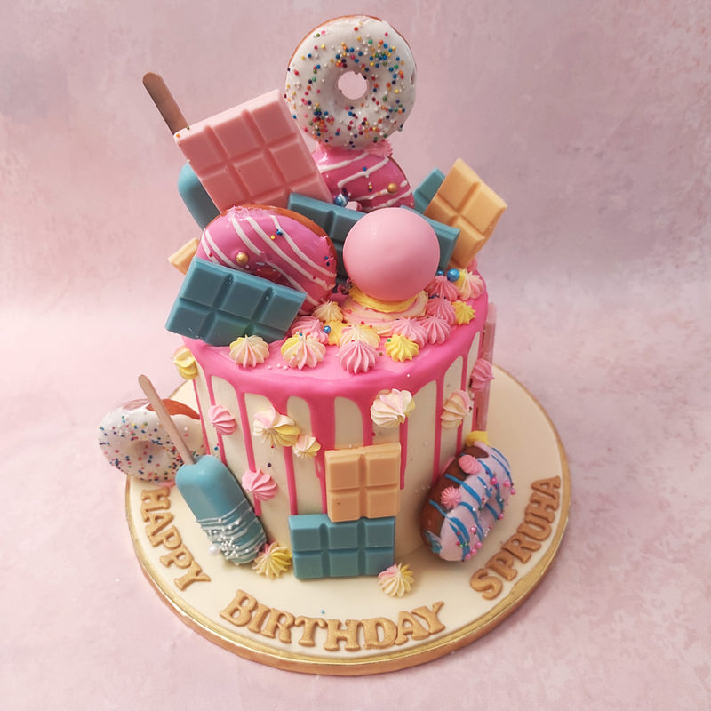  The colorful candy bars and cakesicles add a playful touch to this already-adorable dessert. And let's not forget the sprinkled donuts on top of this donut birthday cake for kids