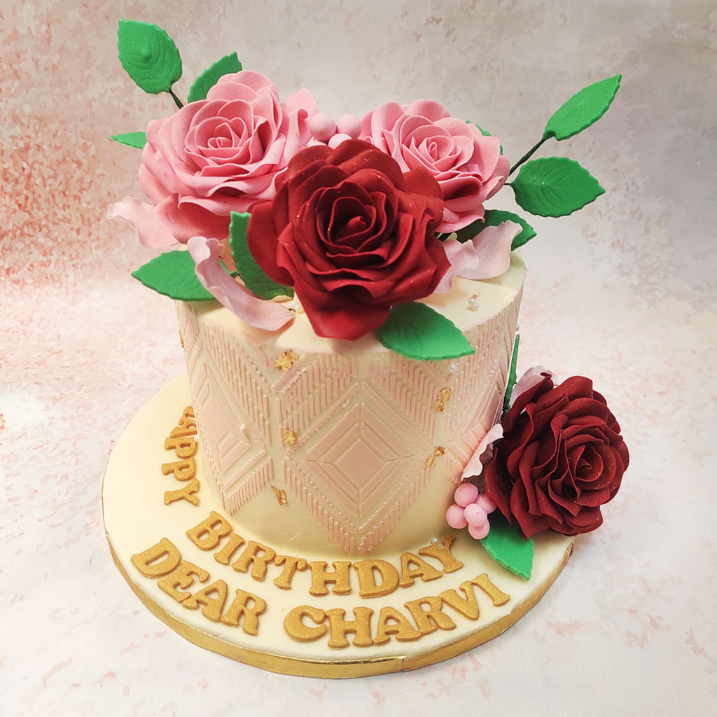 The base of this Edible Rose Wife's Birthday Cake features an intricate geometric pattern, embossed in soft blush tones, creating a sophisticated and elegant canvas. 