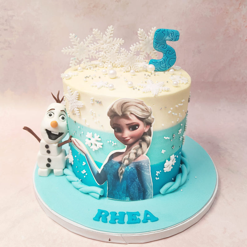 At the base, a braided ribbon adds an elegant touch, evoking Elsa's iconic hairstyle on this Blue Ombre Cake.