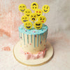 The  Emoticon Cake is adorned with a smooth, light blue drip icing cascading down the sides, adding a dynamic and visually appealing element. 